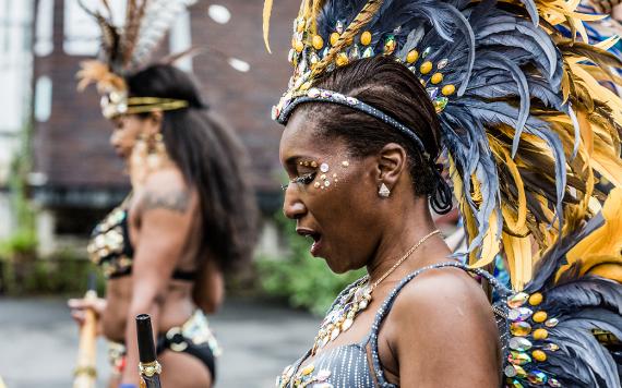 Woman at 2017 Caribbean Carnival, dressed in black and gold costume for parade.