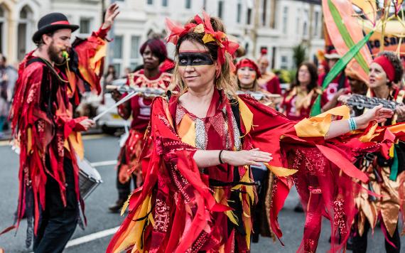 Group dressed in red costumes, dancing in 2017 Caribbean Carnival parade.