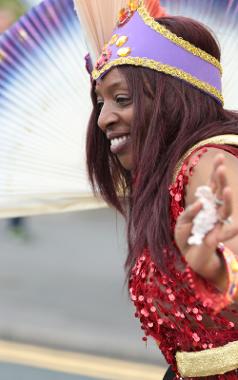 Woman in 2017 Caribbean Carnival parade dancing, dressed in red sequins and headdress.