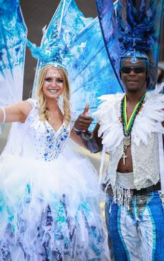 Woman and man smiling for camera, dressed in dramatic white and blue costumes at 2019 carnival.