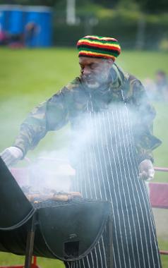 2019 food vendor on Moor Park, wearing Jamaican hat and grilling chicken.