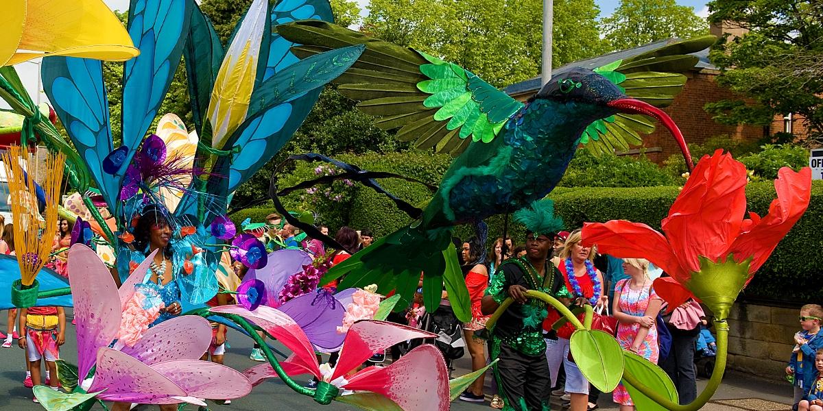 Former Preston Caribbean Carnival parade with people dressed in extravagant bird costumes.