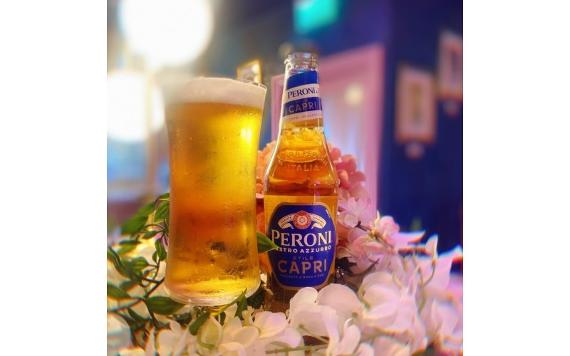 A large glass and beer bottle surrounded by flowers on a table inside Le Fleur Bar