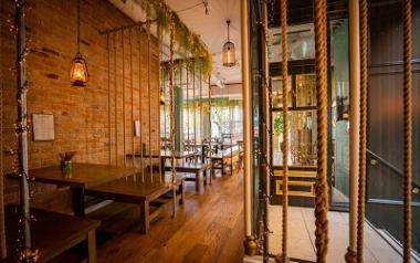 A view inside Mowgli Street Food showing tables for four and swinging benches held by thick ropes