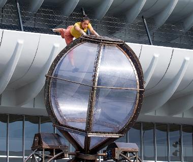 Performer balancing on top of Timeless installation