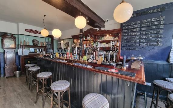 A view inside The Moorbrook Inn showing the bar and a drinks board of cask ales and beers