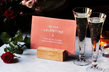 Restaurant table with card saying be our Valentine. After all, no one does romance like the French