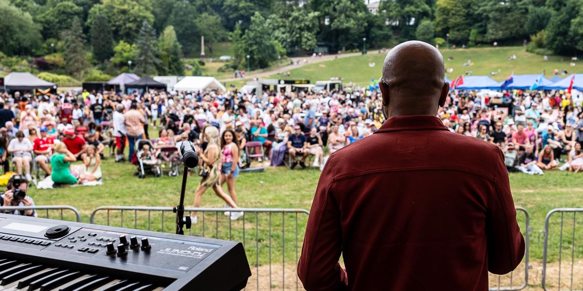 Looking out at a crowd from behind a musician playing music on a stage