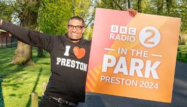 Richie Anderson holding up Radio 2 in the Park banner on Moor Park