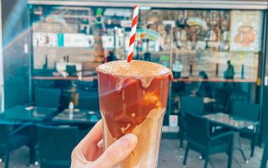 An iced Argentinian cappuccino held up in front of the outside of Cafuné