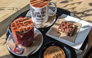 Two cups of coffee and 2 sweet treats on a tray in the sun from Cedarwood Coffee