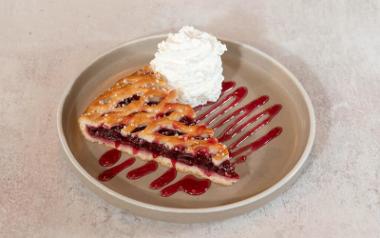 A plate with a slice of cherry pie and a heap of whipped cream from Cherry Pie Coffee Shop