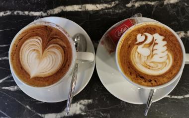 Two coffees in cups and saucers with latte art decorations on top