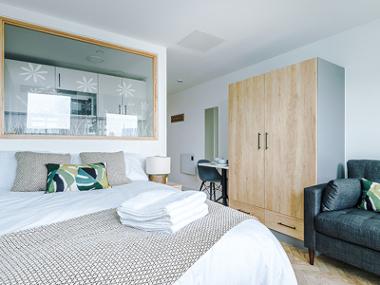 A City Studios Preston studio room with a double bed, wardrobe, sofa and small desk and chair