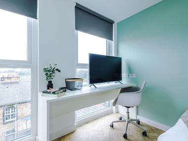 A City Studios Preston studio room window with a TV on a desk with a desk chair