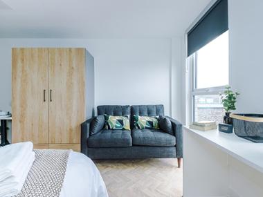 A City Studios Preston studio room with a sofa and wardrobe next to a large window