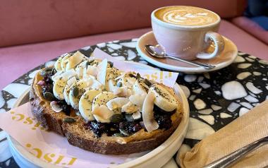 A plate of peanut butter, jam and banana pieces on toast with a mug of coffee from Rise Coffee House