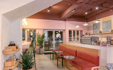 A view of the seating area with a bench, small tables and tall chairs inside Rise Coffee House