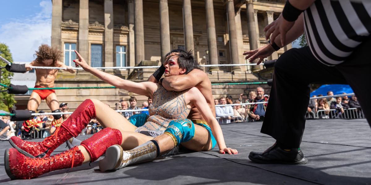 Two wrestlers inside a ring competing in a wrestling match in front of The Harris on the Flag Market