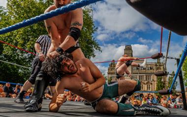 A wrestler pinning down another wrestler in a wrestling ring on the Flag Market