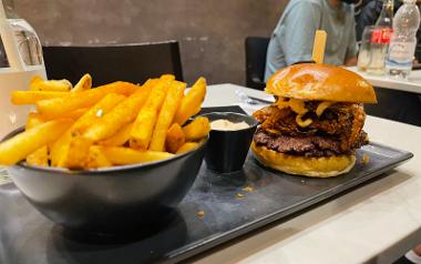 A burger and fries with a dipping sauce on a plate from IceBurg Preston