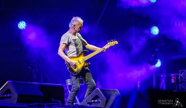 Sting playing guitar on stage