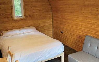 A view of a bed and couch inside the glamping pod at Beacon Fell View Holiday Park