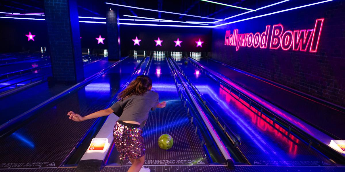 A girl throwing a bowling ball down a bowling alley in Hollywood Bowl