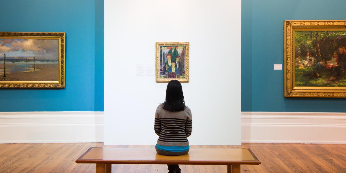 Woman sat on a bench looking at paintings in the Harris Museum's art gallery.