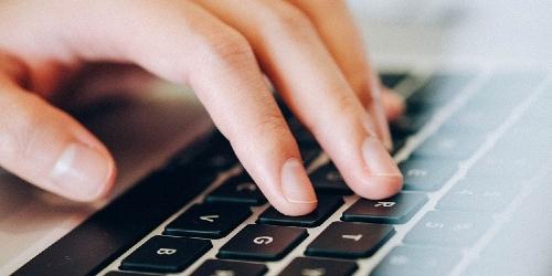 Woman's hand typing in details using laptop keyboard.