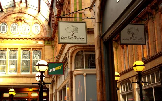 Olive Tree Brasserie and Subway hanging signs inside Miller Arcade.