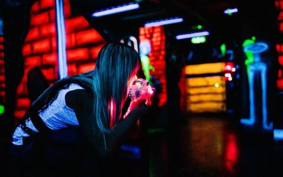 Girl crouching behind wall in End of Days laser tag arena.