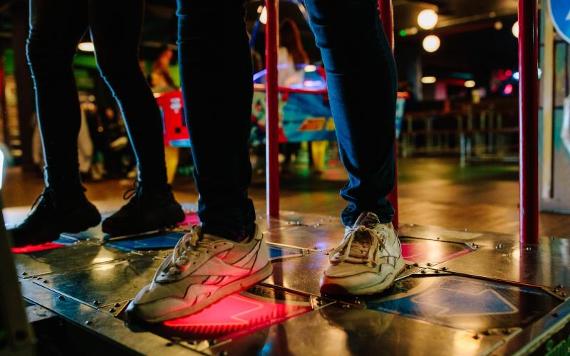 Close-up of people's feet on dance machine in Level Preston's arcade.