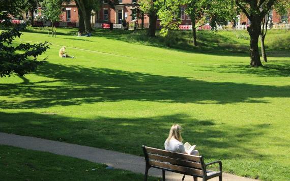 Woman reading a book on bench in Winckley Square Gardens.