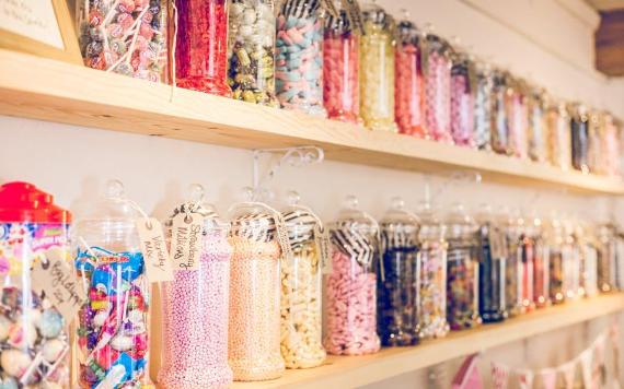 Many colourful sweets in jars on a shelf inside Samlesbury Hall shop.