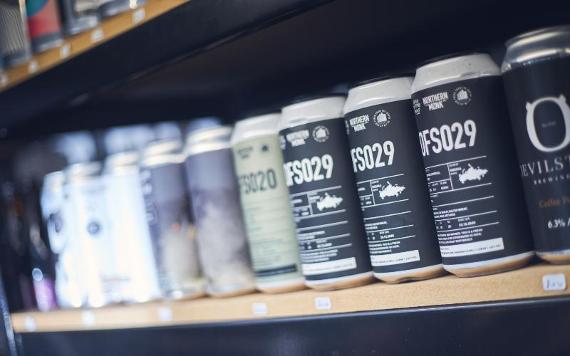 Row of beer cans on shelf inside Priest Town Brewing.