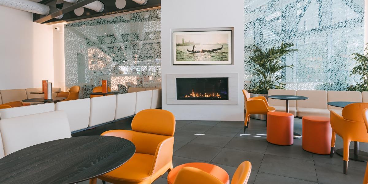 Orange seating and modern fire inside Italian Orchard's dining area.