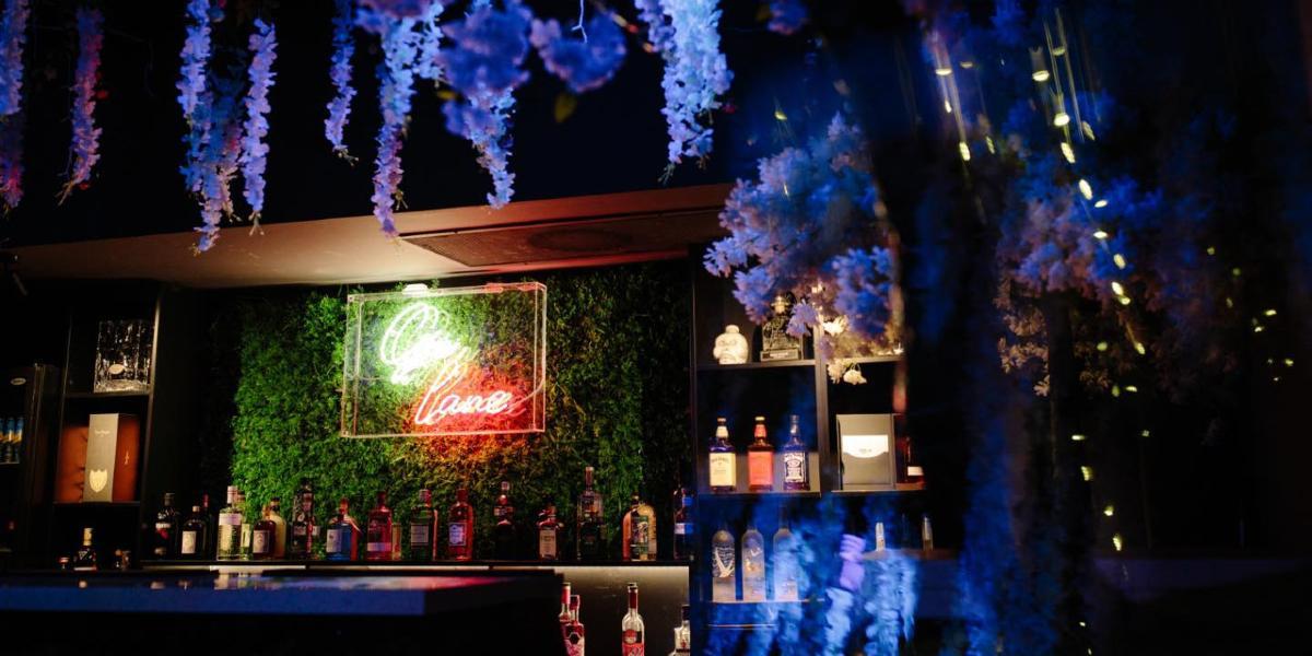 Review bar decorated with neon sign and fake plants.