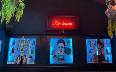 Portraits lit up in blue and red neon sign reading "lost dreams".