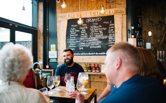 Group of people of all ages smiling and enjoying drinks in The Orchard, Preston.