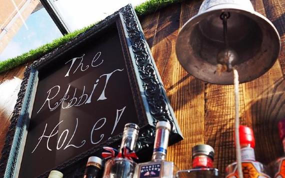 Bell, Gins, and The Rabbit Hole sign behind bar.