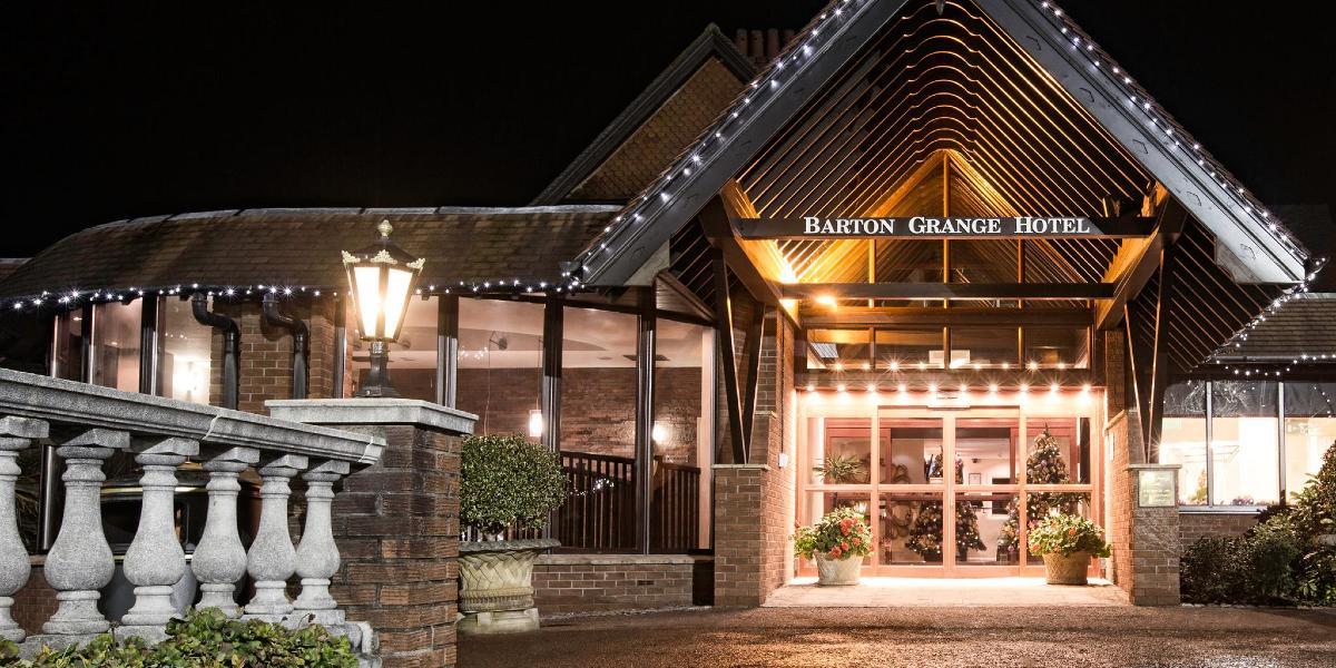 Front entrance to Barton Manor Hotel, lit up at night.