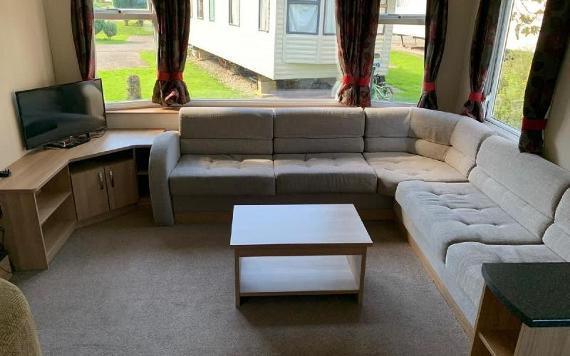 Corner sofa, tv, and coffee table inside Beacon Fell View caravan.