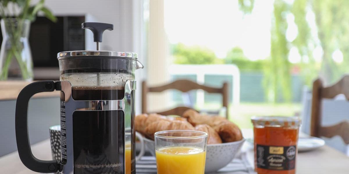 Cafetiere, orange juice, and croissants on kitchen table in one of Bedzzz locations.