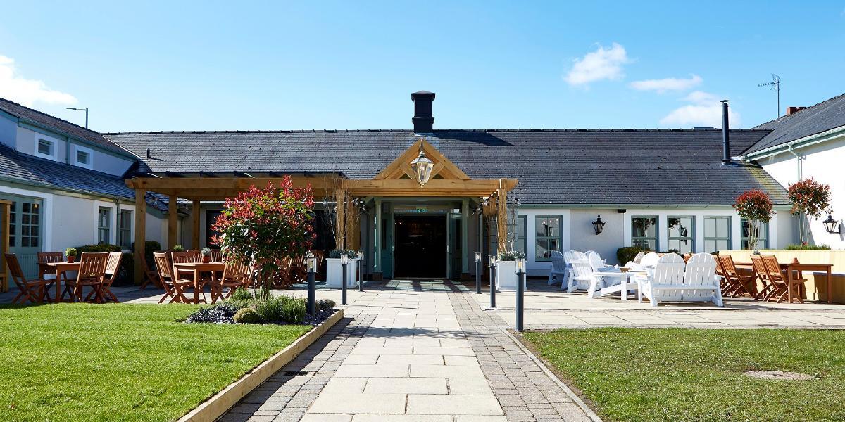 Entrance to Bluebird Inn with grass area and outdoor seating outside.