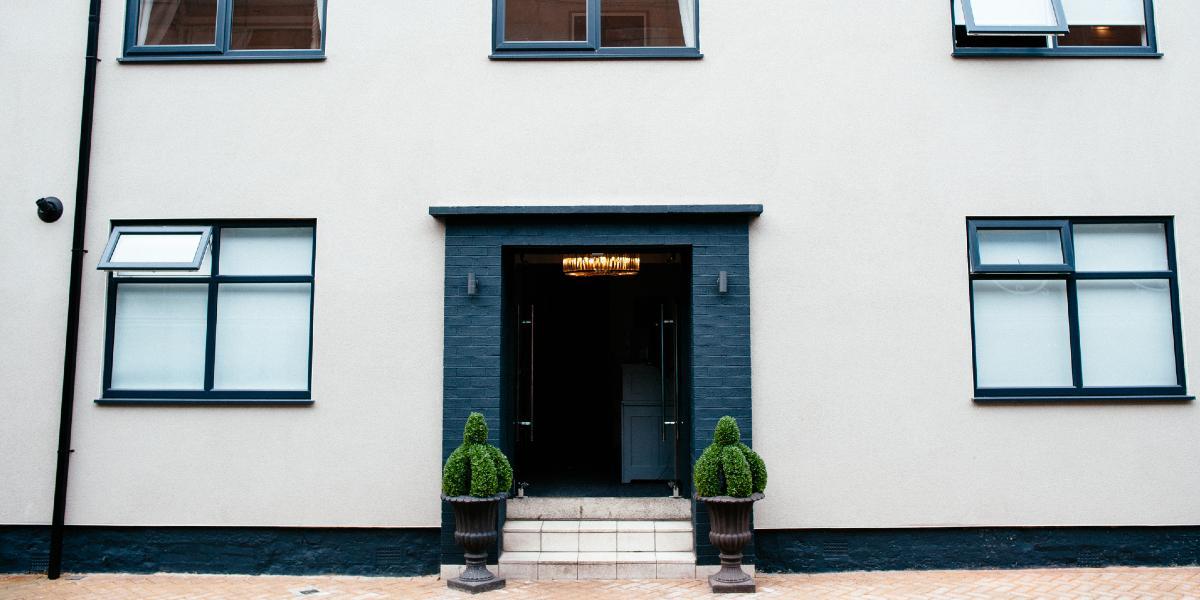 Black and white exterior of No.10 Preston with potted plants.