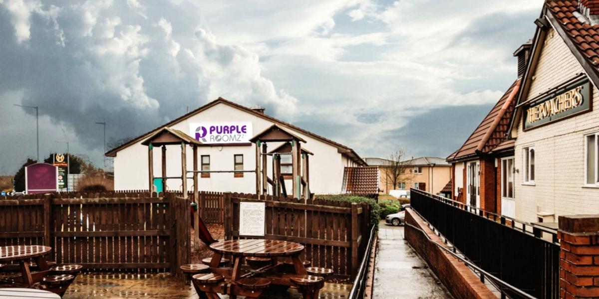 Outside Purple Roomz hotel, with children's play area and next door pub.