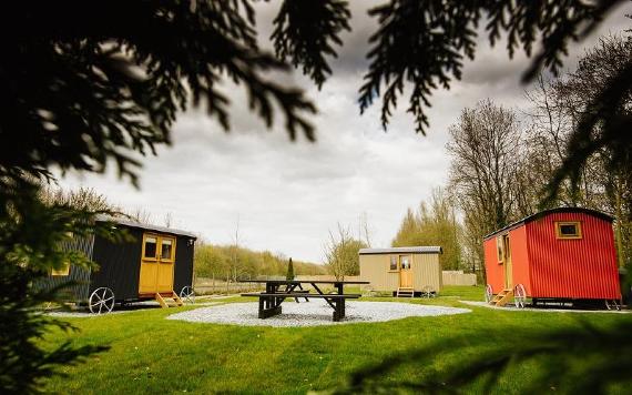 View of Samlesbury Hall's three shepherd huts through the trees.