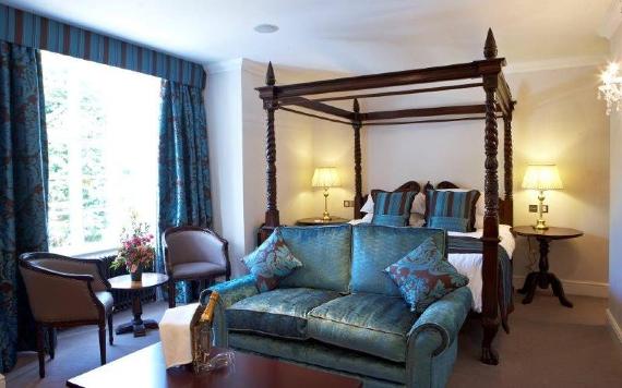 Villa Wrea Green hotel room with four poster bed, brown and blue decor, and a bottle of Champagne.