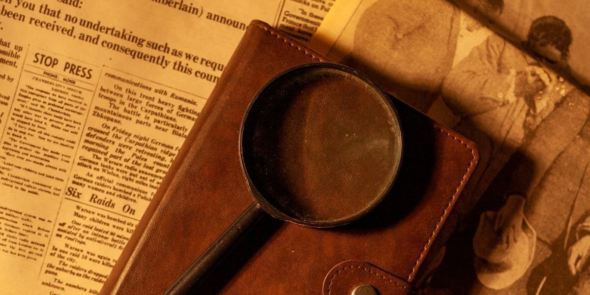 Magnifying glass on notebook and newspapers.